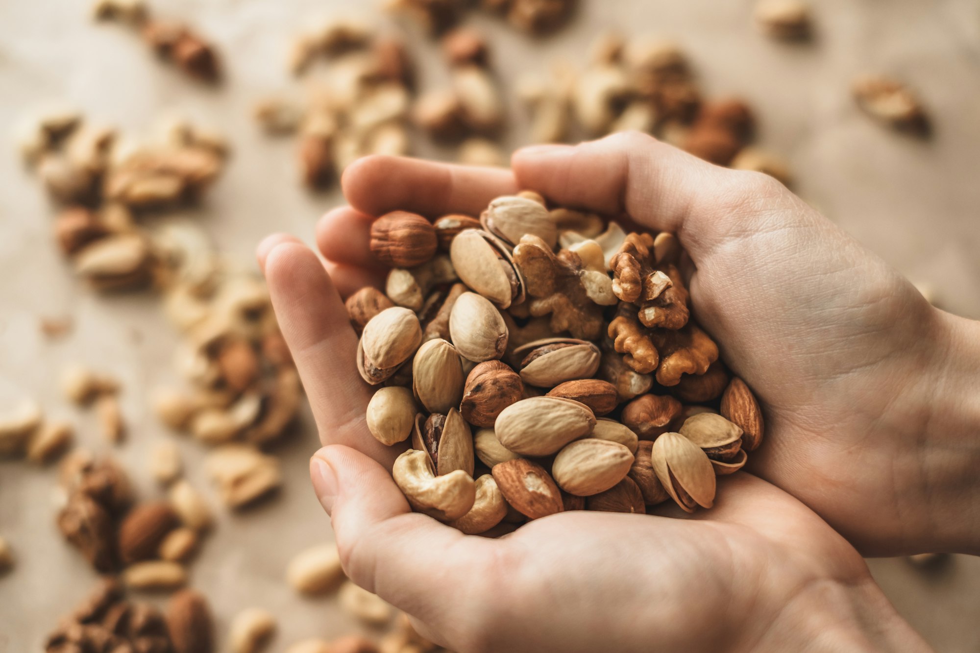 Different types of nuts, nut mix of almonds, hazelnuts, cashews, peanuts in hands.